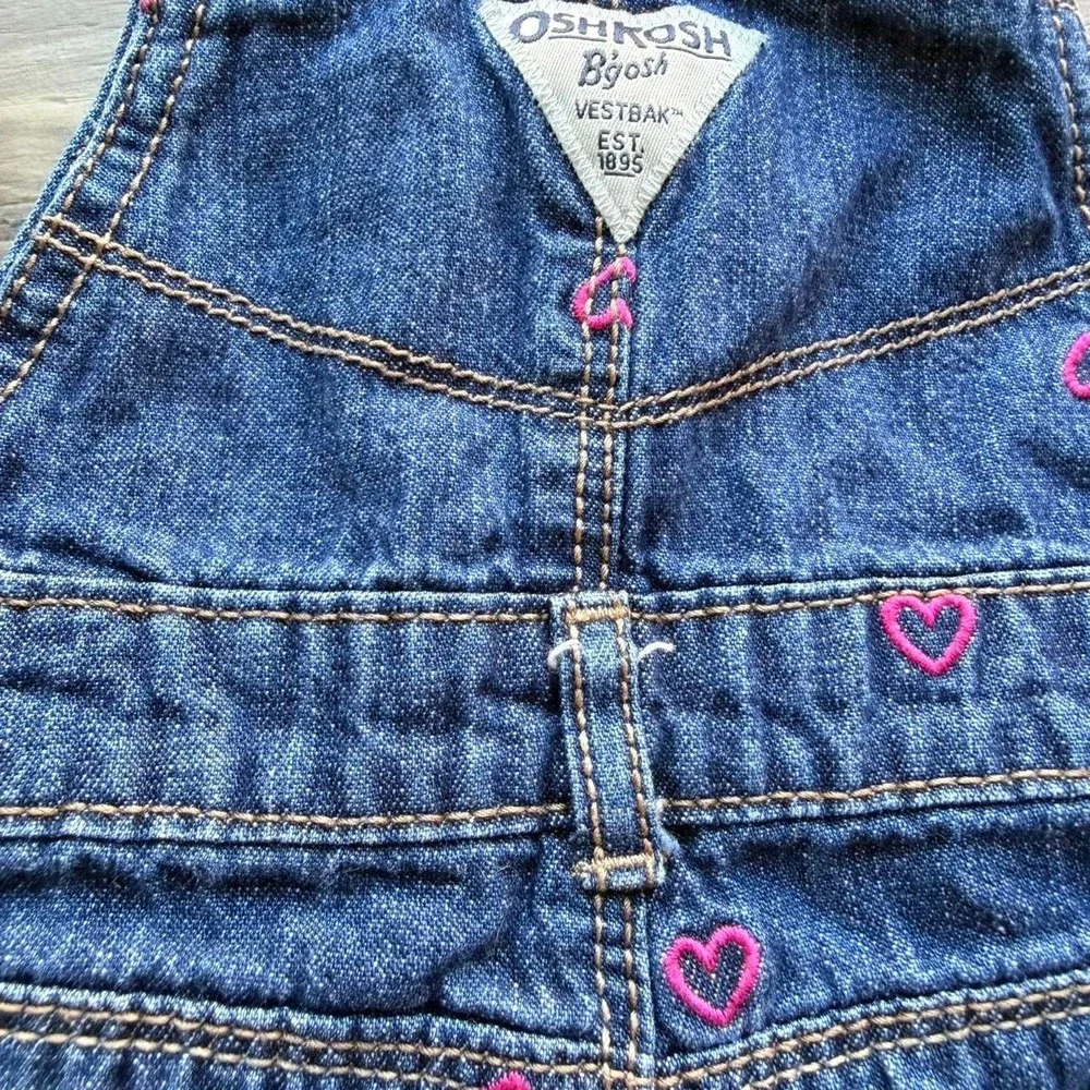 OshKosh B'gosh blue denim overalls with pink heart embroidery